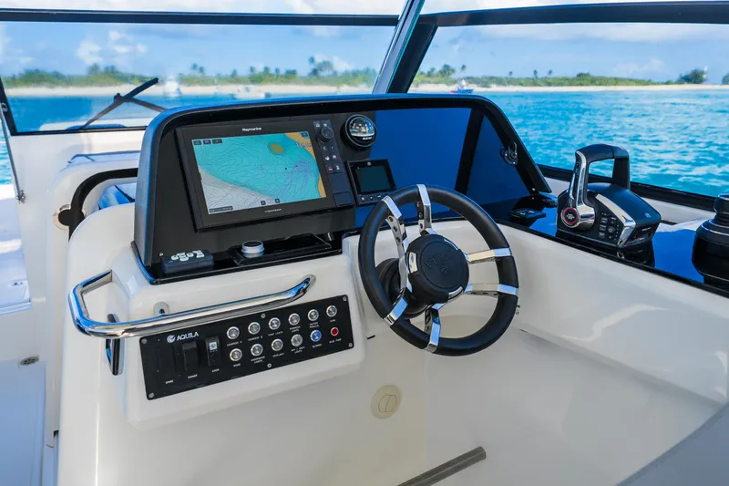 Slide: The Image of 2023 Aquila 36 Sport helm with navigation display and controls, overlooking ocean view. - 22