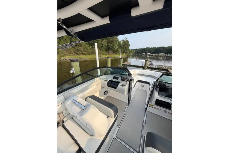 Slide: The Image of 2023 Regal LX2 boat interior with sleek seating and modern dashboard, docked by a serene lake. - 11