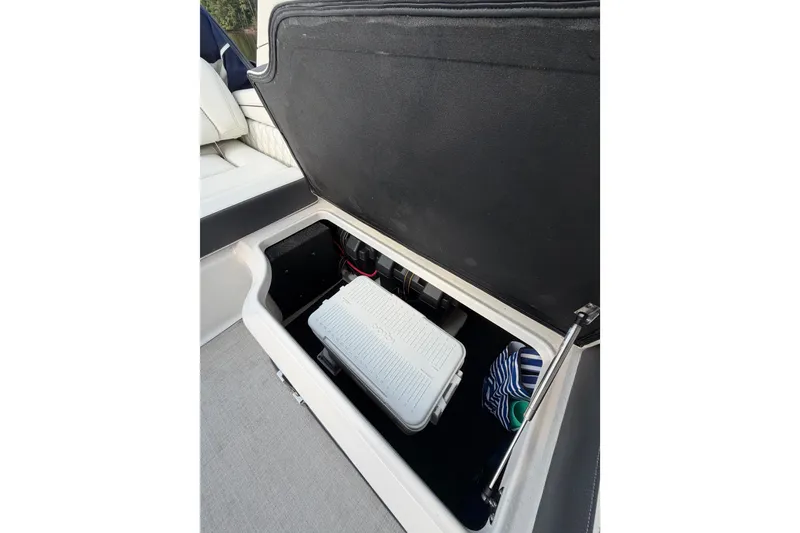 Slide: The Image of Open storage compartment in 2023 Regal LX2 boat with cooler and striped bag. - 13