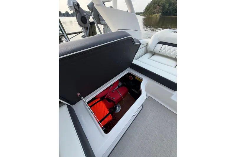 Slide: The Image of 2023 Regal LX2 boat storage compartment with open lid, revealing interior equipment. - 12