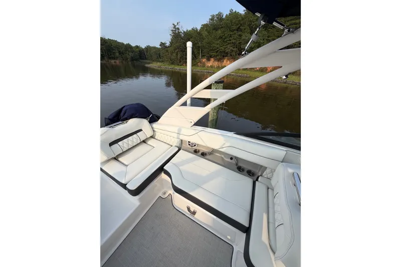 Slide: The Image of 2023 Regal LX2 boat interior with white seating, docked by a serene lake. - 10