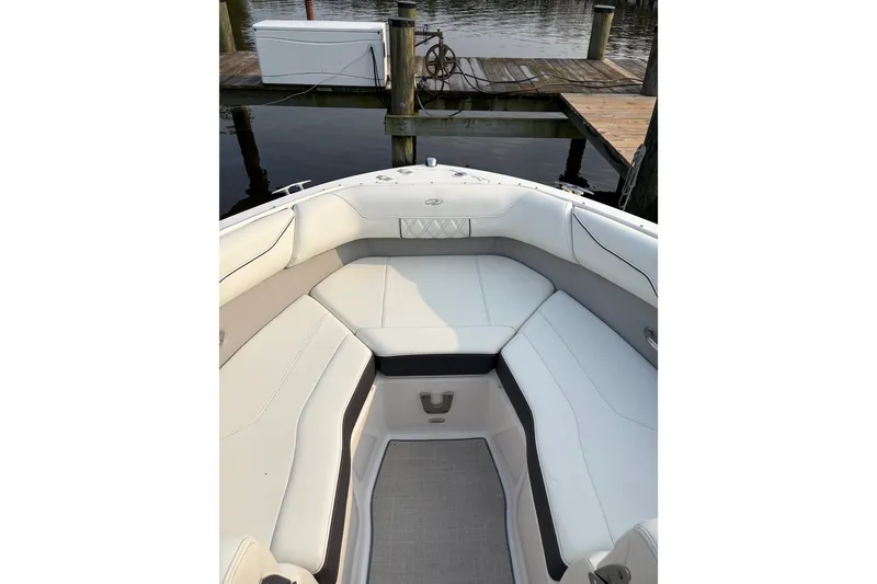 Slide: The Image of 2023 Regal LX2 boat interior with white seating, docked by a wooden pier. - 5