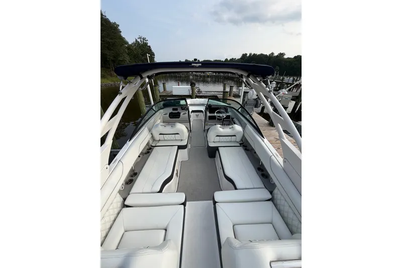 Slide: The Image of 2023 Regal LX2 boat interior with white seating, docked by a serene waterfront. - 20
