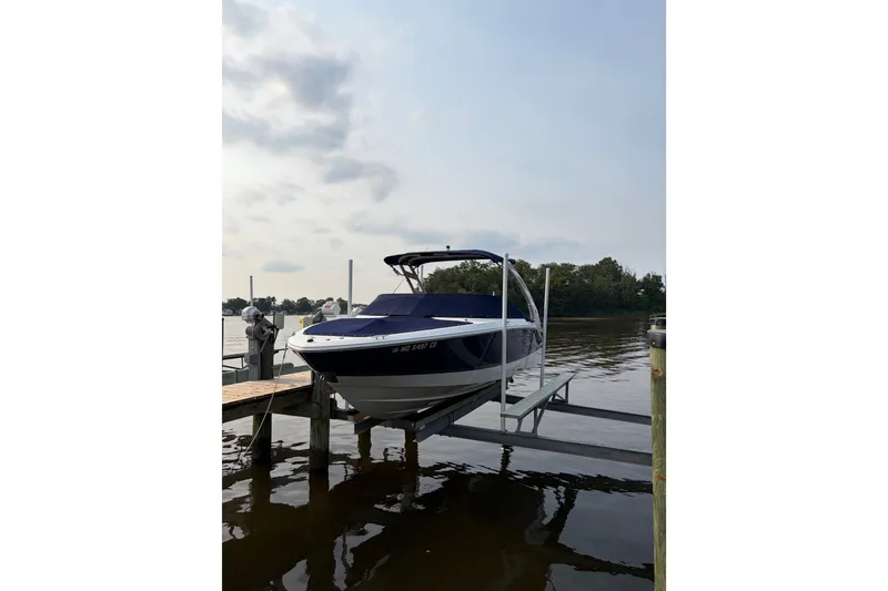 The Image of 2023 Regal LX2 boat docked on a lift by a calm lake. - 0