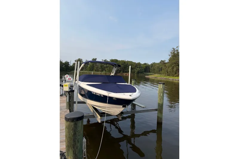 Slide: The Image of 2023 Regal LX2 boat docked on a serene lake with lush greenery. - 1