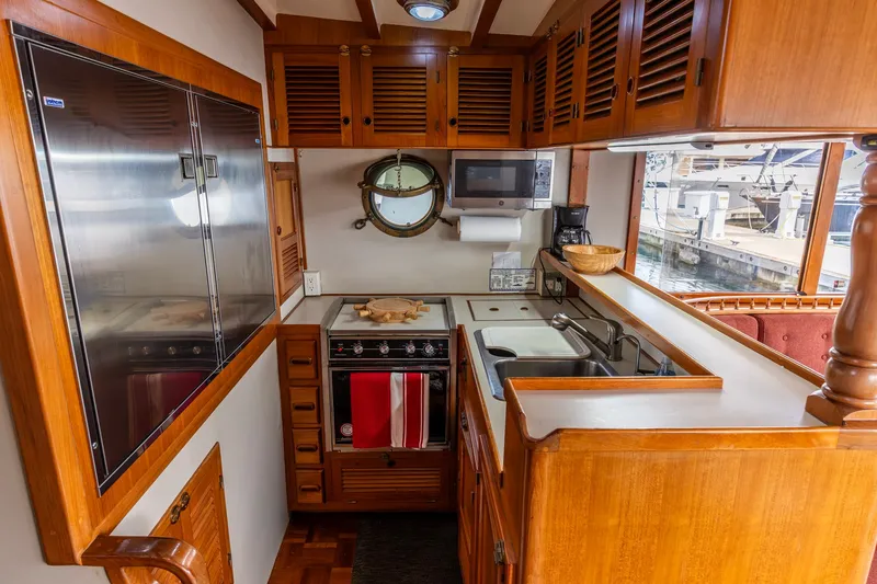 Slide: The Image of Cozy 1990 Kadey-Krogen 42 yacht kitchen with wooden cabinetry, stove, and porthole window. - 5