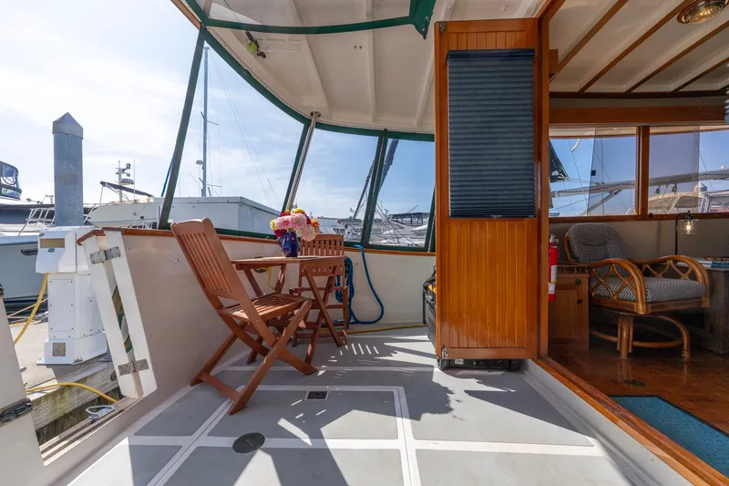Slide: The Image of Kadey-Krogen 42 yacht deck, 1990 model, featuring wooden furniture and floral centerpiece. - 48