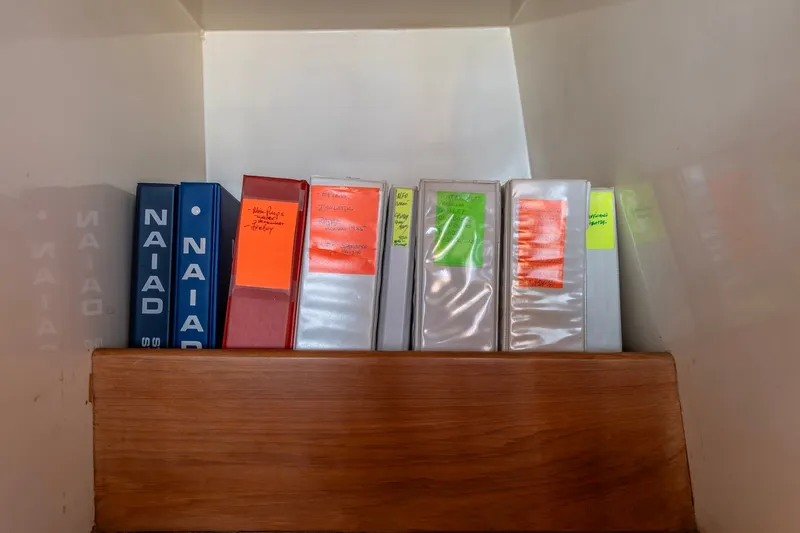 Slide: The Image of Binders on a shelf inside a 1990 Kadey-Krogen 42 boat. - 20
