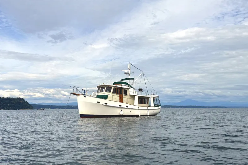 The Image of 1990 Kadey-Krogen 42 yacht anchored on calm waters under a cloudy sky. - 1