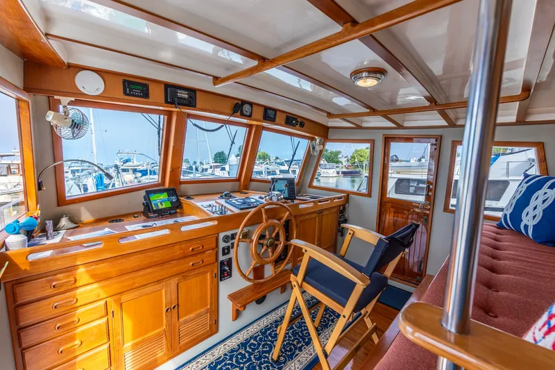 Slide: The Image of Cozy 1990 Kadey-Krogen 42 yacht interior with wooden helm, nautical decor, and marina view. - 6