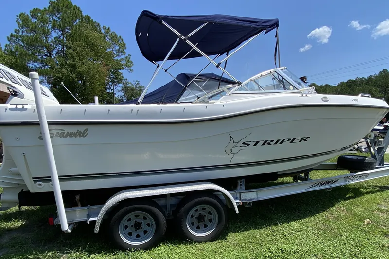 Slide: The Image of 2000 Seaswirl Striper 2100 boat on trailer, parked outdoors under blue sky. - 3