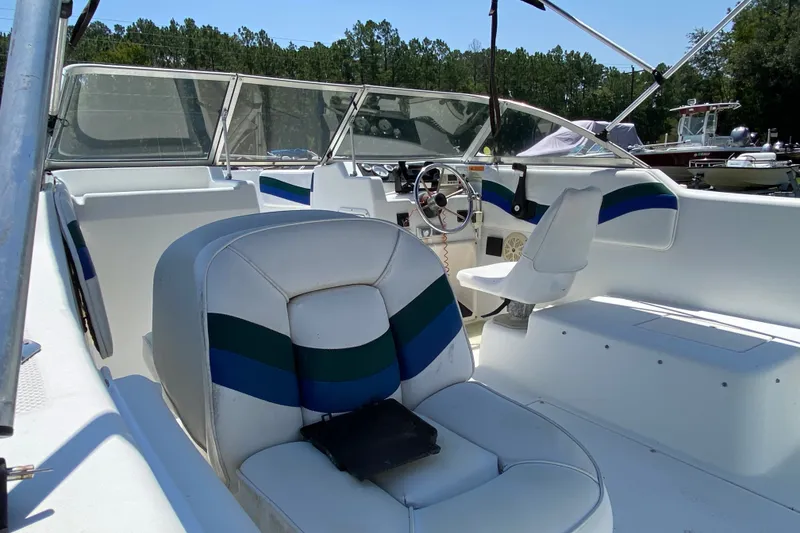Slide: The Image of Interior of a 2000 Seaswirl Striper 2100 boat with white seating and steering wheel. - 8