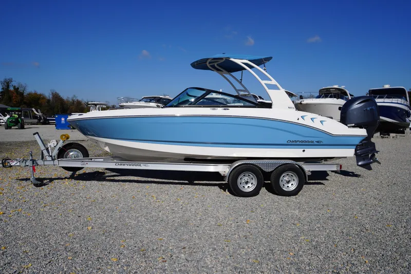 The Image of 2026 Chaparral 21 SSi OB boat on trailer, blue and white design, parked outdoors. - 0