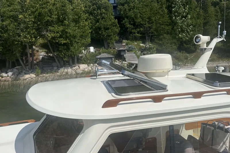 Slide: The Image of 2005 Hinckley Picnic Boat 36 EP docked near lush greenery. - 29