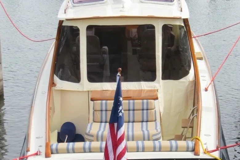 Slide: The Image of 2005 Hinckley Picnic Boat 36 EP docked, featuring striped seating and an American flag. - 35