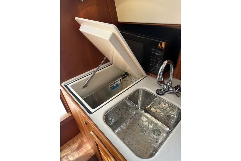 Slide: The Image of 2005 Hinckley Picnic Boat 36 EP galley with sink, microwave, and storage compartment. - 21