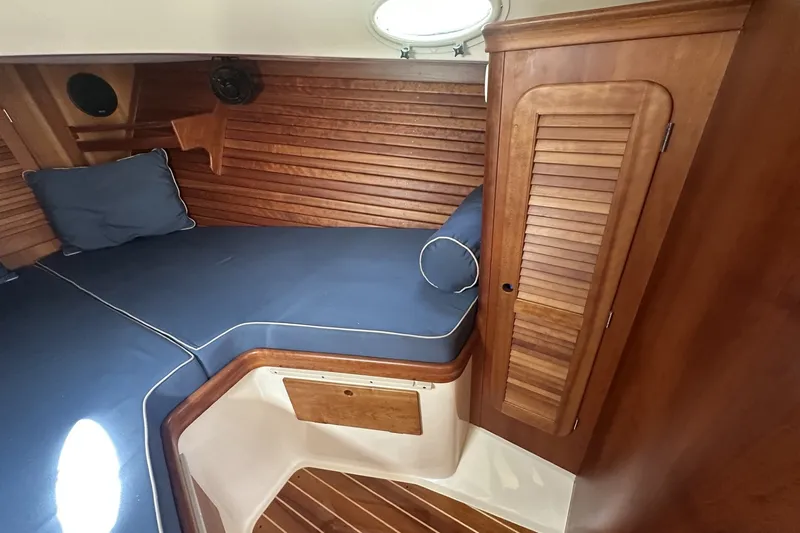 Slide: The Image of 2005 Hinckley Picnic Boat 36 EP cabin with blue cushions and wooden interior. - 25