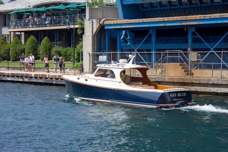 Slide: The Image of 2005 Hinckley Picnic Boat 36 EP cruising near a waterfront with onlookers. - 37