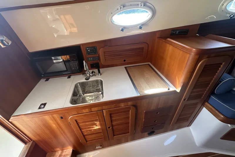 Slide: The Image of 2005 Hinckley Picnic Boat 36 EP galley with wood cabinetry and modern appliances. - 20