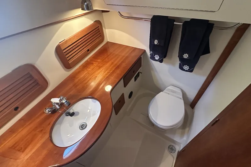 Slide: The Image of 2005 Hinckley Picnic Boat 36 EP bathroom with wooden countertop and nautical-themed towels. - 27