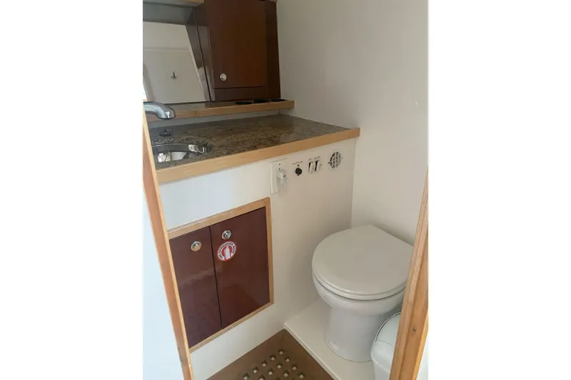 Slide: The Image of 2008 Contender 38 Express boat bathroom with sink, toilet, and wooden cabinetry. - 72