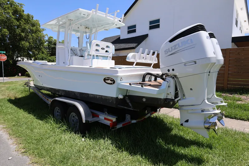 Slide: The Image of 2024 Dusky 278 XFY boat on trailer with Suzuki outboard motor, parked on grass. - 3