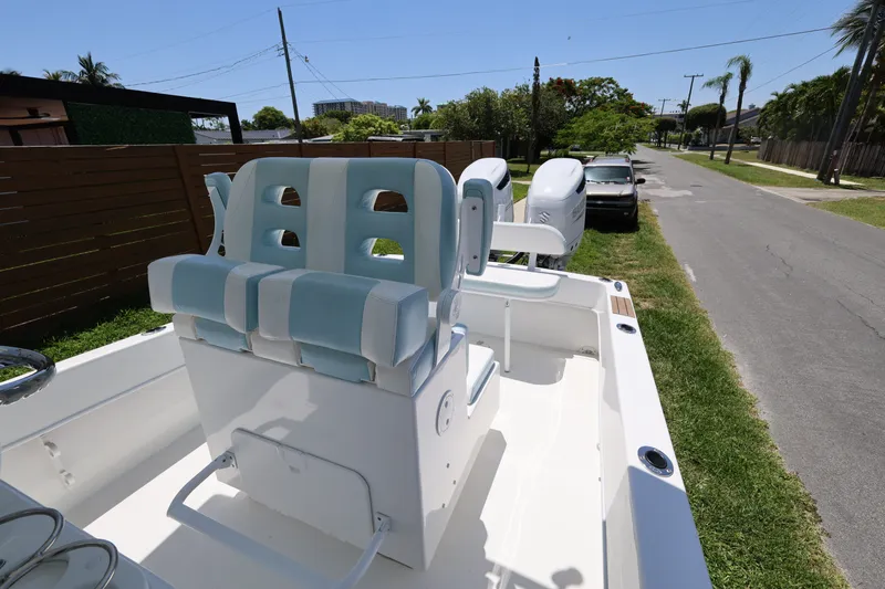 Slide: The Image of 2024 Dusky 278 XFY boat with dual engines and cushioned seating, parked on a grassy roadside. - 16