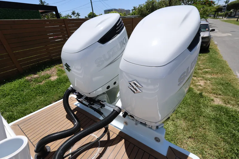 Slide: The Image of Twin Suzuki outboard motors on a 2024 Dusky 278 XFY boat, parked outdoors. - 18