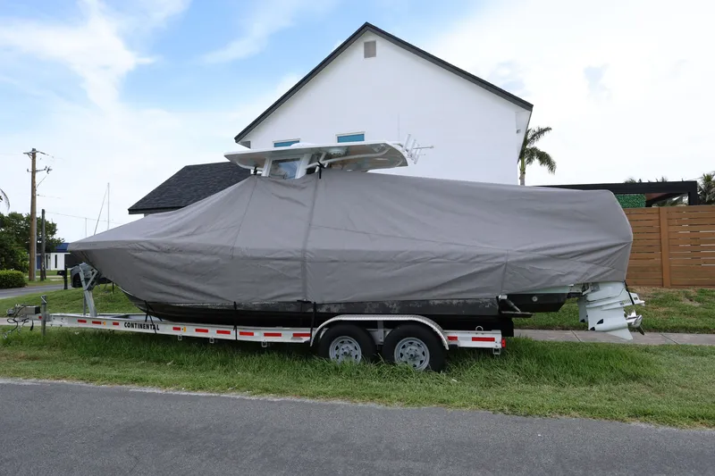 Slide: The Image of Covered 2024 Dusky 278 XFY boat on trailer, parked beside a house. - 19