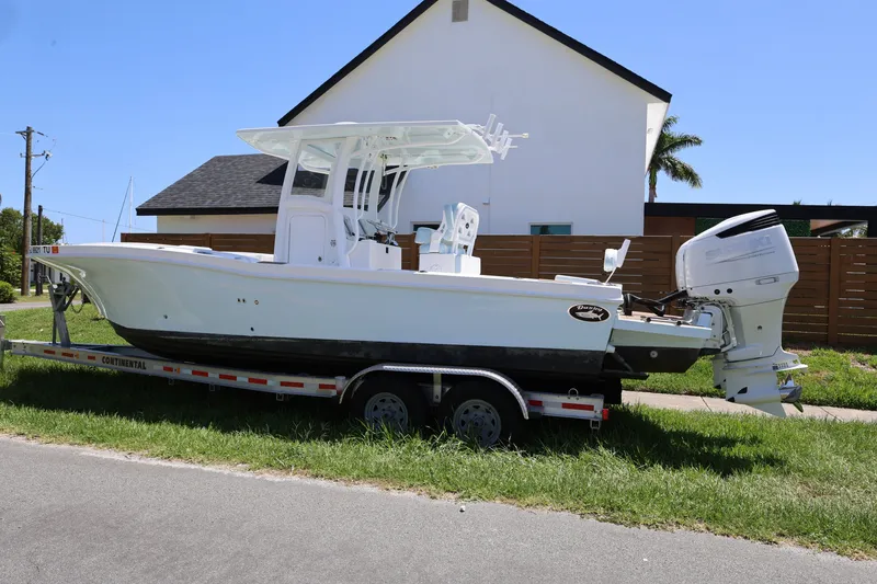 Slide: The Image of 2024 Dusky 278 XFY boat on trailer, parked near a modern house. - 2