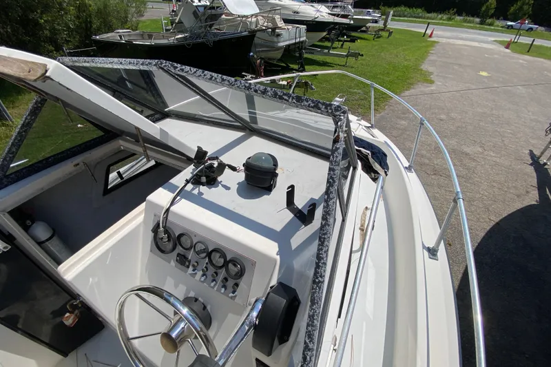Slide: The Image of 1991 Horizon 204 boat cockpit with steering wheel and control panel, parked on grass. - 8