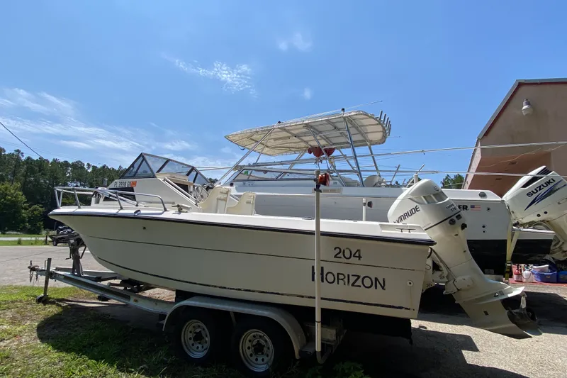 The Image of 1991 Horizon 204 boat on trailer with outboard motors, parked outdoors under clear sky. - 1