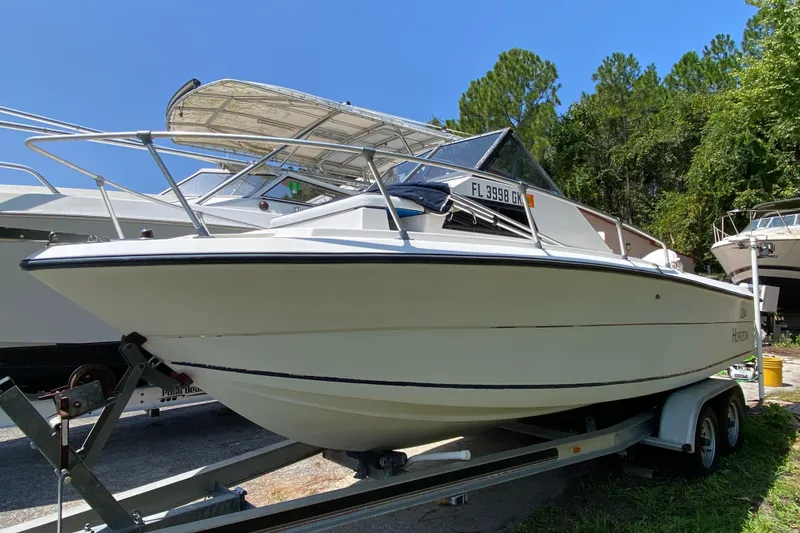 Slide: The Image of 1991 Horizon 204 boat on trailer, parked outdoors under clear blue sky. - 2