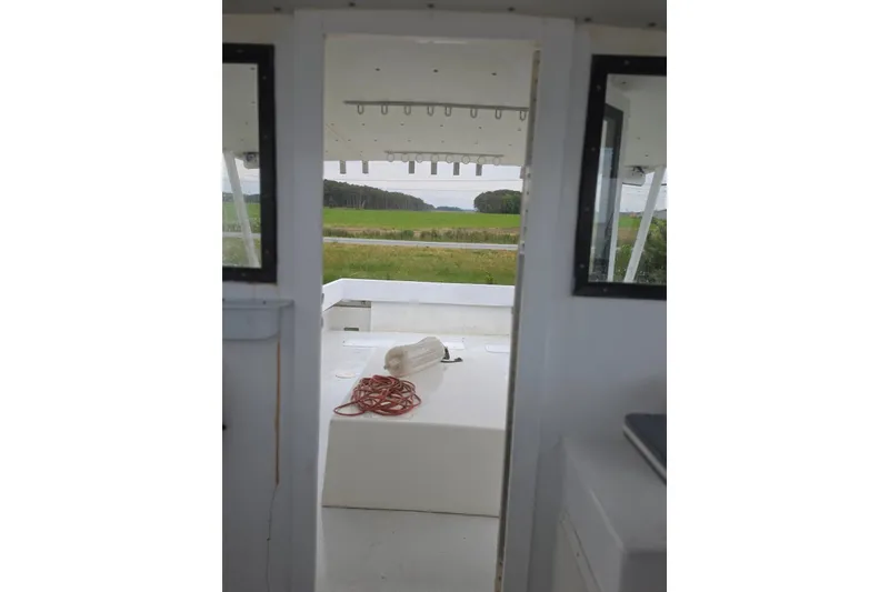 Slide: The Image of 1966 Uniflite Sportfisherman boat interior with open deck view, rope, and countryside background. - 14