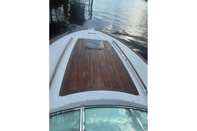 Slide: The Image of 2006 Chris-Craft Corsair 33 boat deck with wooden finish, docked by the water. - 43