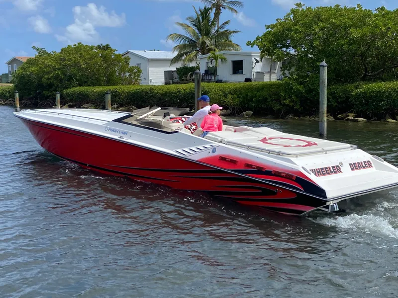 The Image of 2006 Fountain 42 Executioner speedboat cruising on a sunny day near lush greenery. - 0