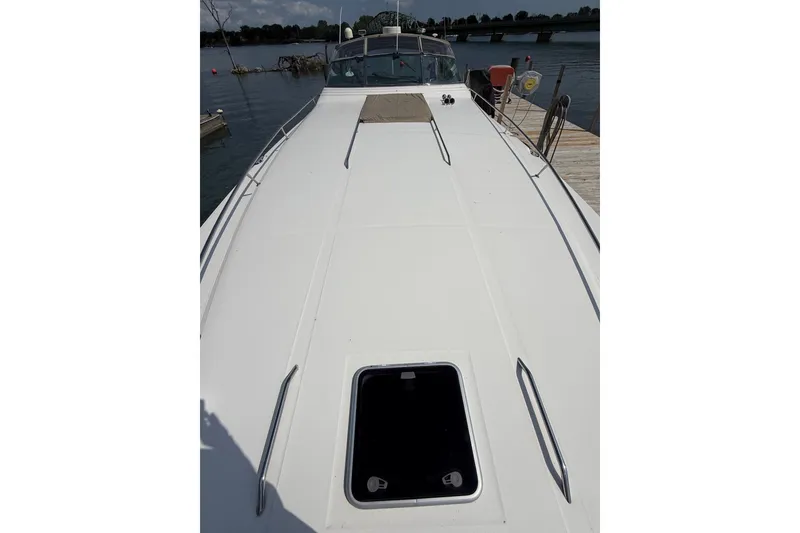 Slide: The Image of 1991 Sea Ray 630 Super Sun Sport yacht docked by a serene lake. - 6