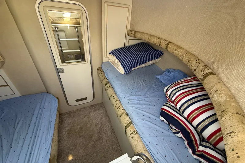 Slide: The Image of 1991 Sea Ray 630 Super Sun Sport cabin with twin beds and striped pillows. - 49