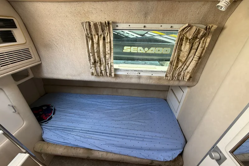 Slide: The Image of 1991 Sea Ray 630 Super Sun Sport cabin with bed, window, and curtains. - 50