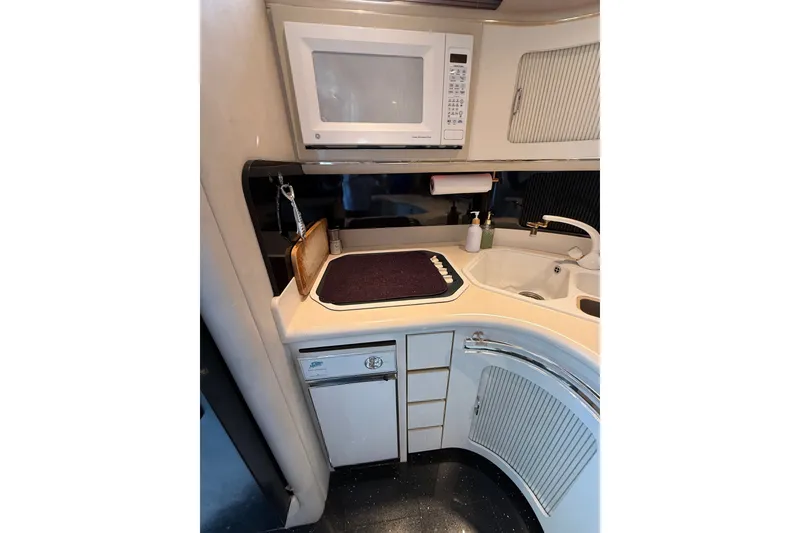 Slide: The Image of Compact kitchen area in a 1991 Sea Ray 630 Super Sun Sport yacht with microwave and sink. - 34