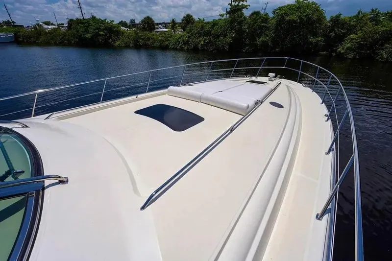 Slide: The Image of 2004 Sea Ray 550 Sundancer yacht deck with sleek design and railing, near lush shoreline. - 4