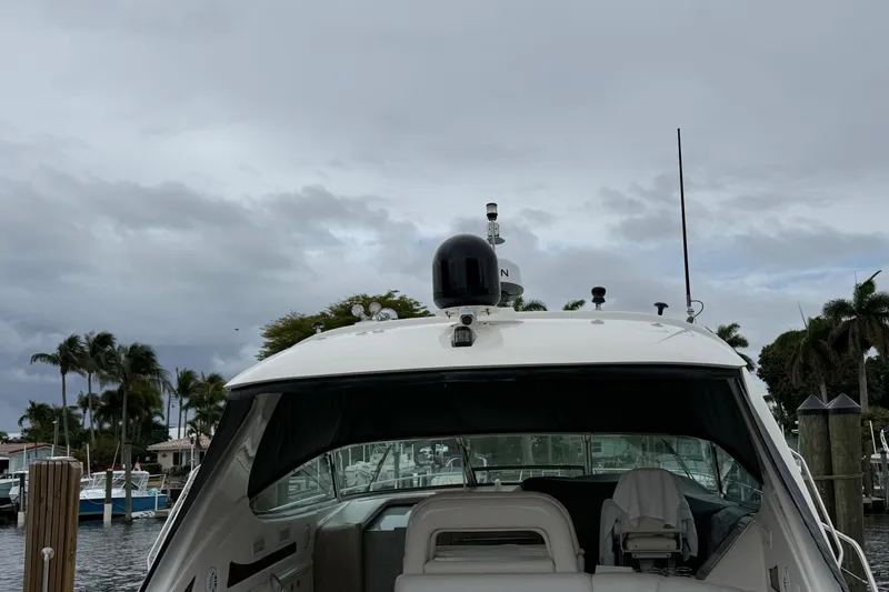 Slide: The Image of 2004 Sea Ray 550 Sundancer yacht docked, with cloudy sky and palm trees in the background. - 46