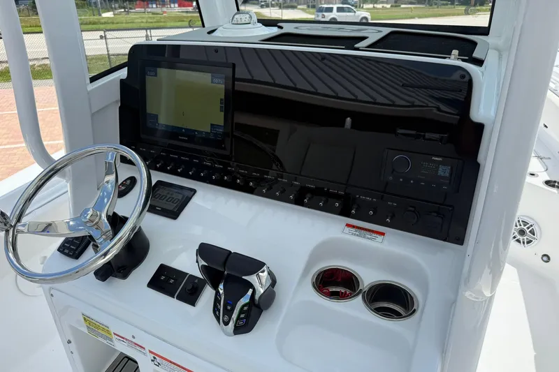 Slide: The Image of 2026 Sea Hunt Gamefish 25 helm with steering wheel, controls, and navigation display. - 18