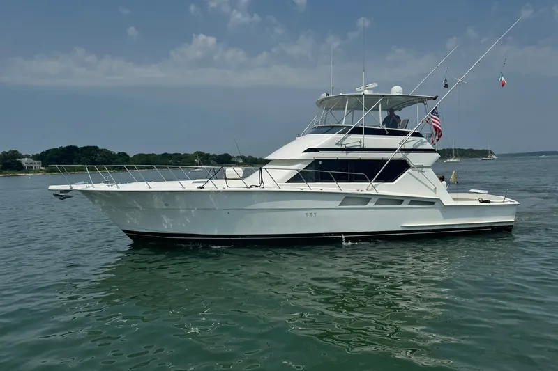 The Image of 1994 Hatteras 54 Convertible yacht on calm water, clear sky background. - 0