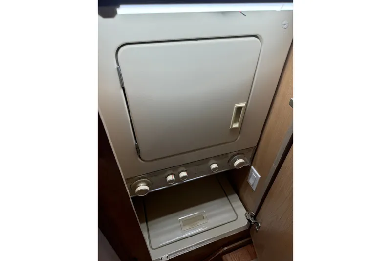 Slide: The Image of Laundry unit inside 1994 Hatteras 54 Convertible yacht, featuring control knobs and door. - 27
