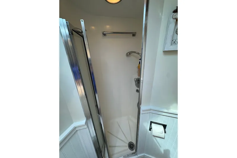 Slide: The Image of Shower area inside 1994 Hatteras 54 Convertible yacht, featuring chrome fixtures and white walls. - 23