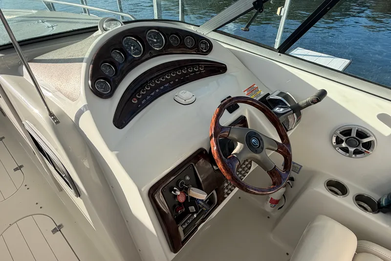 Slide: The Image of 2006 Crownline 290 CR boat dashboard with wood-accented steering wheel and control panel. - 14