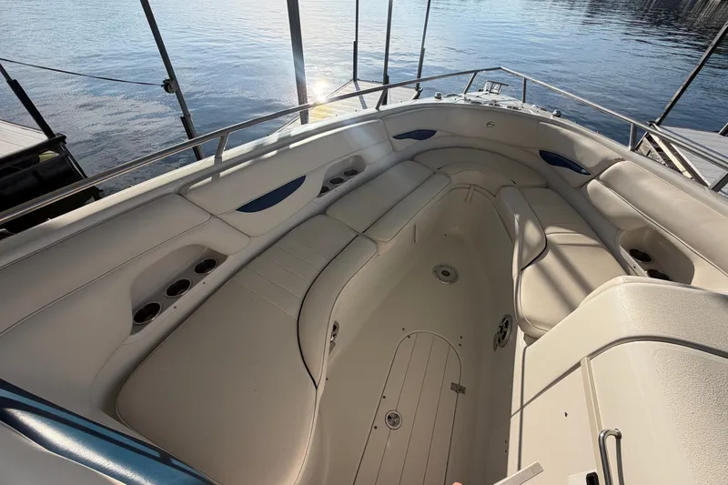 Slide: The Image of 2006 Crownline 290 CR boat interior with spacious seating and cup holders, docked by calm water. - 22