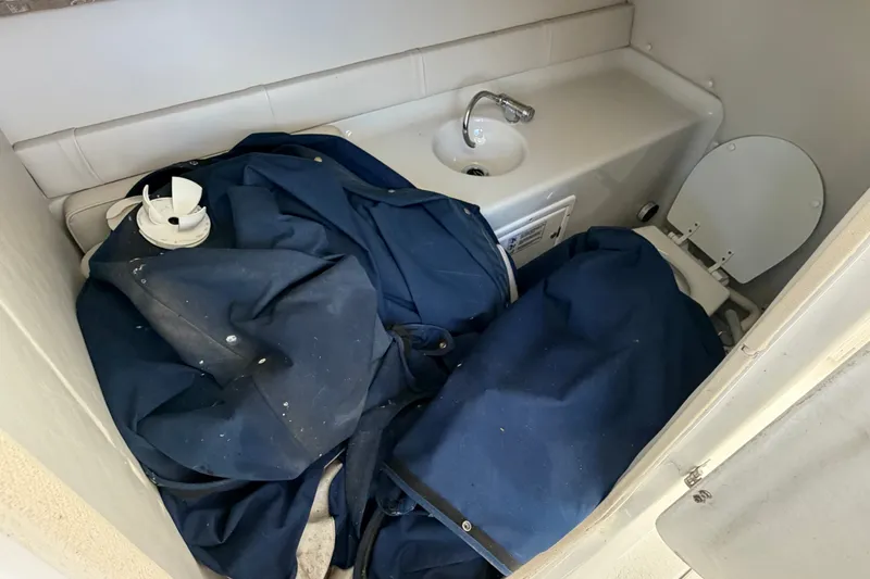 Slide: The Image of 2006 Crownline 290 CR boat bathroom with sink, toilet, and blue fabric storage. - 19