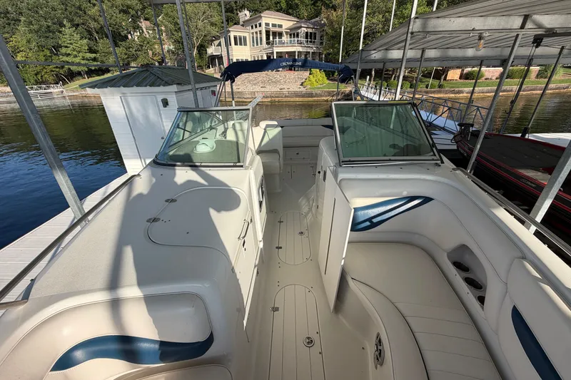 Slide: The Image of 2006 Crownline 290 CR boat interior with white seating and glass windshields at a dock. - 24